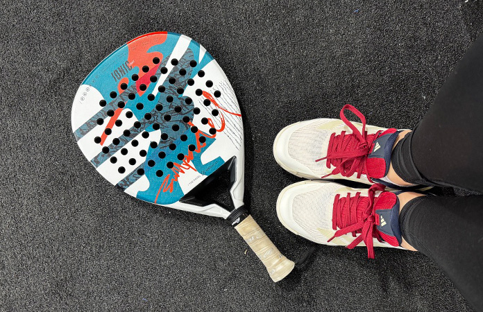 femme de 50 ans qui débute le padel avec raquette sur terrain