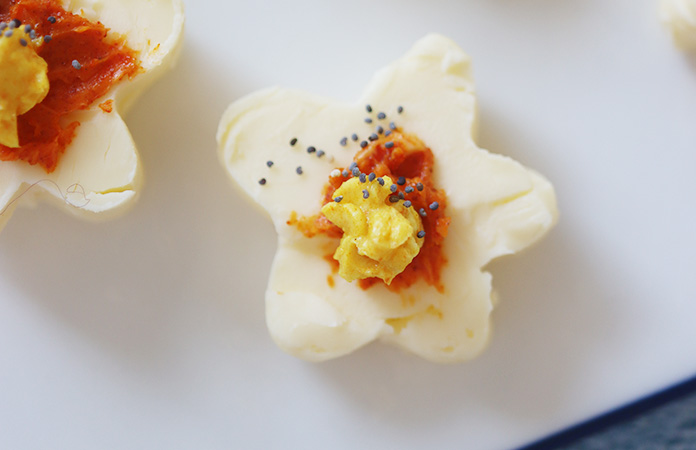 Découpe de beurre coloré avec un emporte-pièce en forme de fleur sur papier cuisson