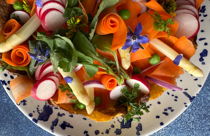 Décoration printanière de quiche avec radis, asperges, fleurs comestibles et herbes fraîches