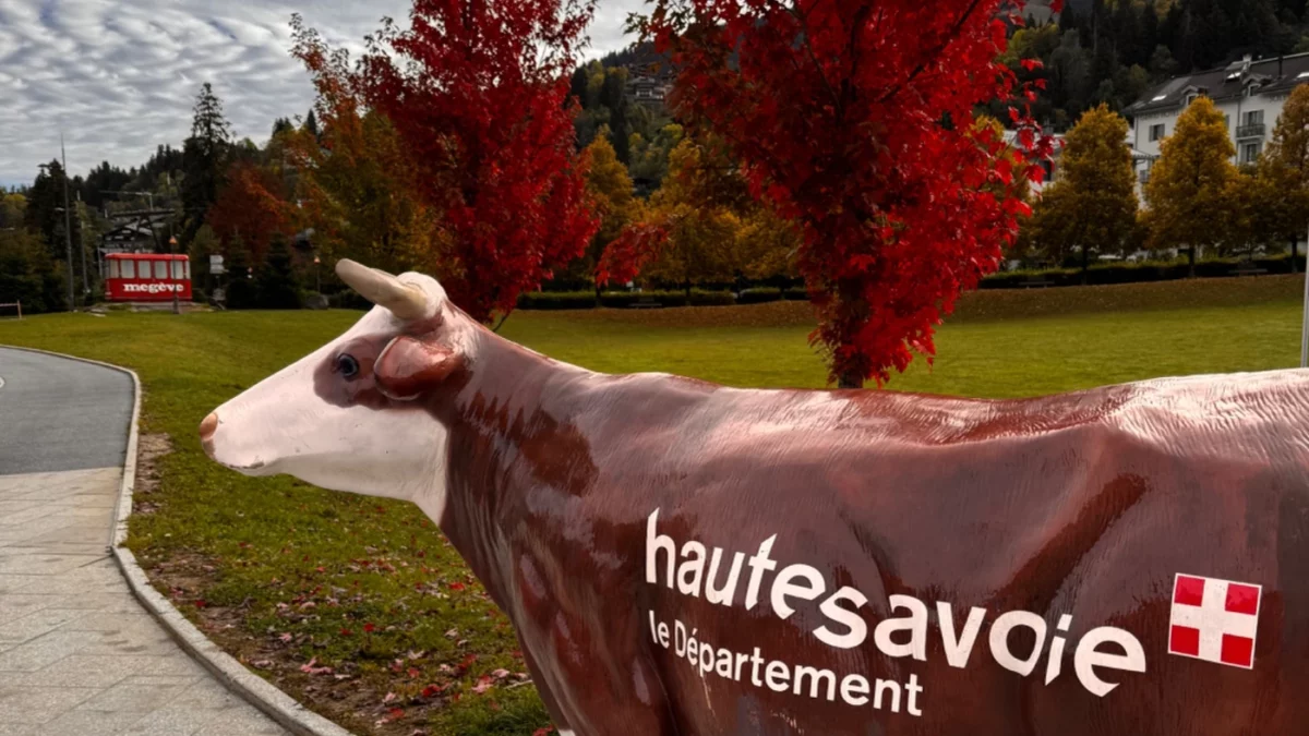 Statue de vache Haute-Savoie devant des arbres rouges d’automne à Megève.